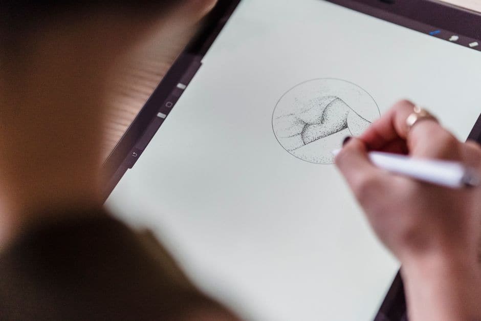 デジタルペンでタブレットに絵を描いている人物の手元