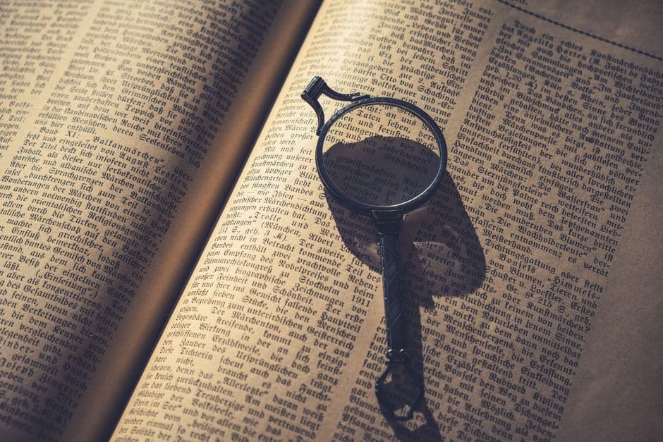 古い本のページに置かれた虫眼鏡が、印刷された文字を拡大している