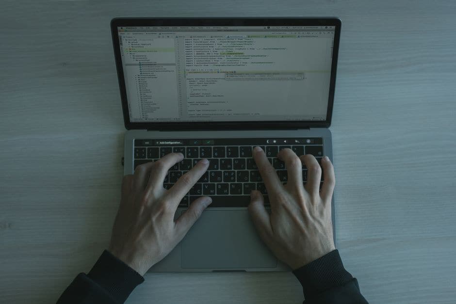 ノートパソコンのキーボードでコードを入力している手元を上から写した写真