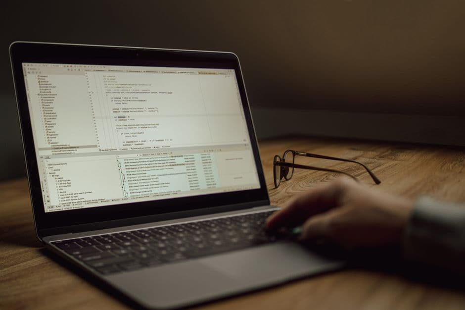 ノートパソコンの画面に表示されたコードとバージョン管理の履歴を見る手元