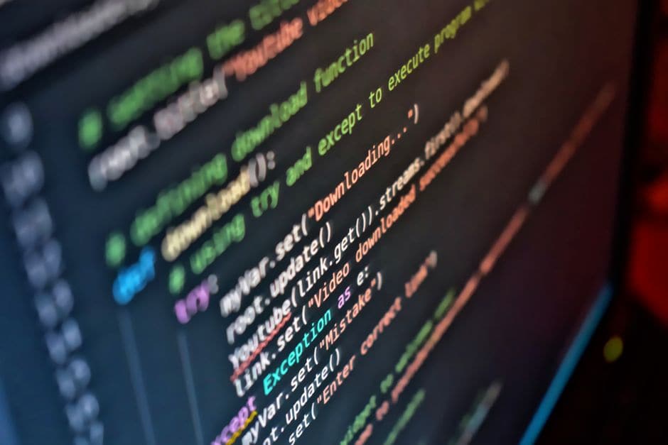 暗い画面いっぱいに表示された、緑や紫のシンタックスハイライトが付いたプログラムコードのクローズアップ写真