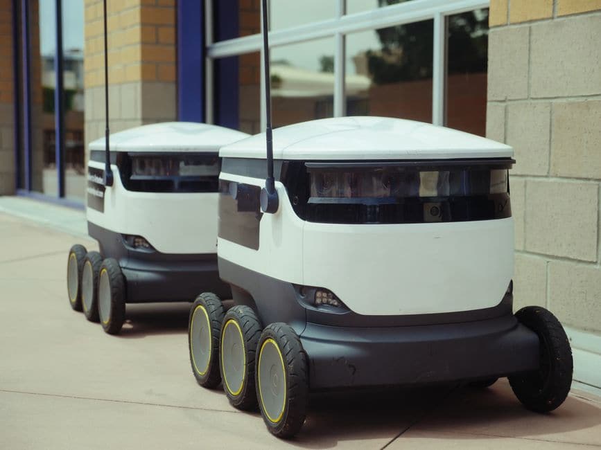 ビルの外に並んで停まっている、自律走行する配送ロボット2台