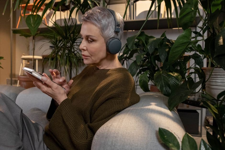 ヘッドホンをつけてスマートフォンを手に、何か話しかけている様子の女性