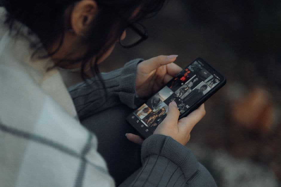 イメージ写真。スマートフォンで写真ギャラリーのグリッド表示をスクロールしている女性の手元。