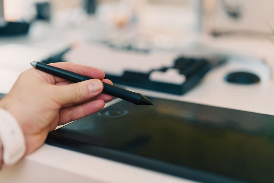 デジタルタブレットにスタイラスペンで触れようとしている手元の接写