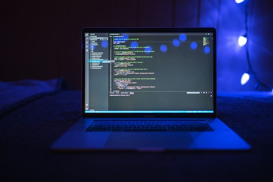 暗い部屋でノートPCの画面にコードが映し出されている写真(イメージ写真)