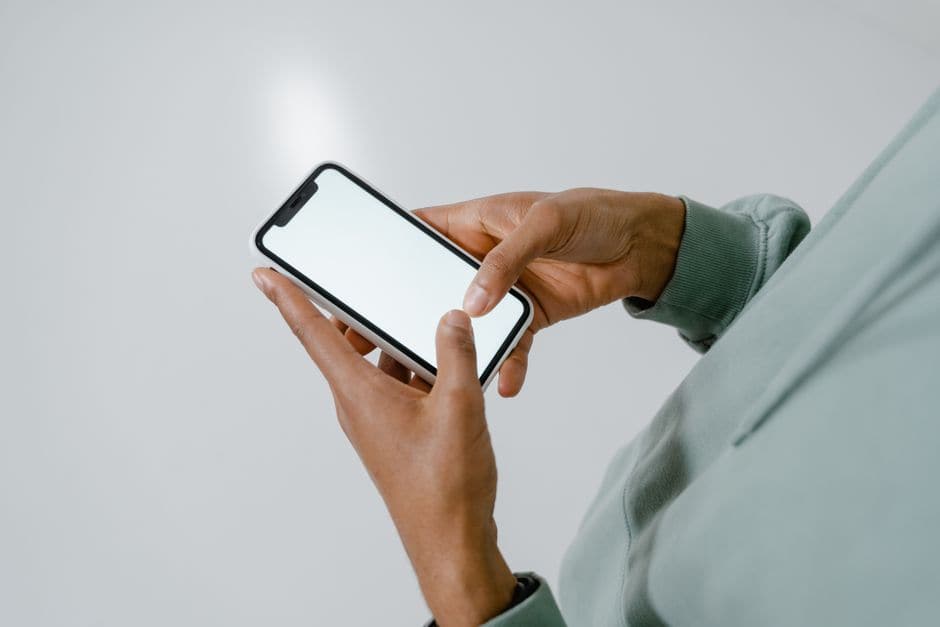屋外で白いスマートフォンを手に持ち、画面を見ている人