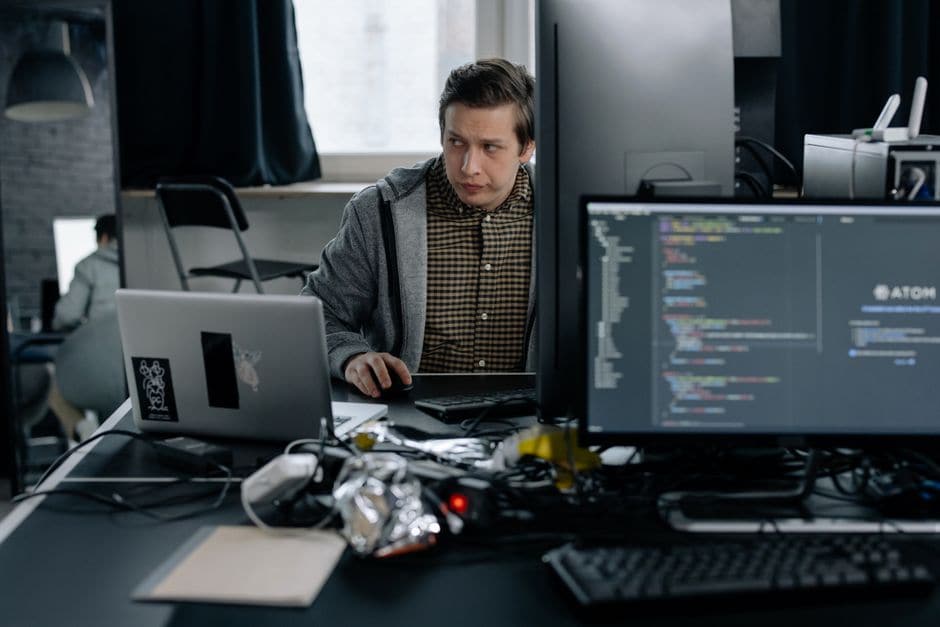 プログラマーがコードの並んだ画面を見ながら、腑に落ちない表情で考え込んでいる