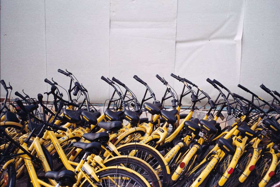屋外に整然と並んで駐輪された黄色いレンタル自転車の列
