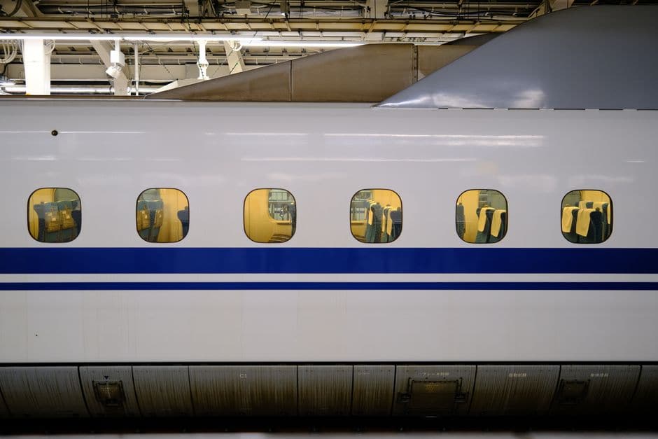 白い車体に青い帯の入った新幹線の側面を、駅のホームで間近から写した写真