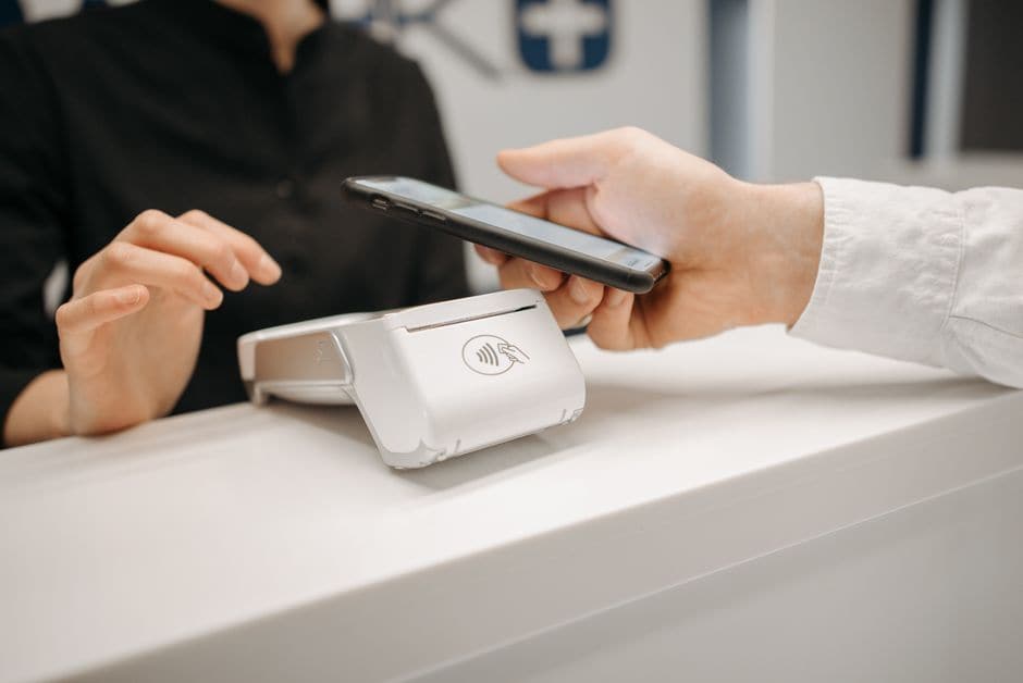 イメージ写真。店頭の決済端末に、非接触決済マークが表示された面でスマートフォンをかざしている接写。