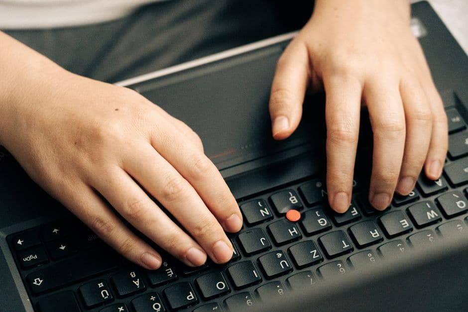 ノートパソコンのキーボードを両手でタイプしている手元(イメージ写真)