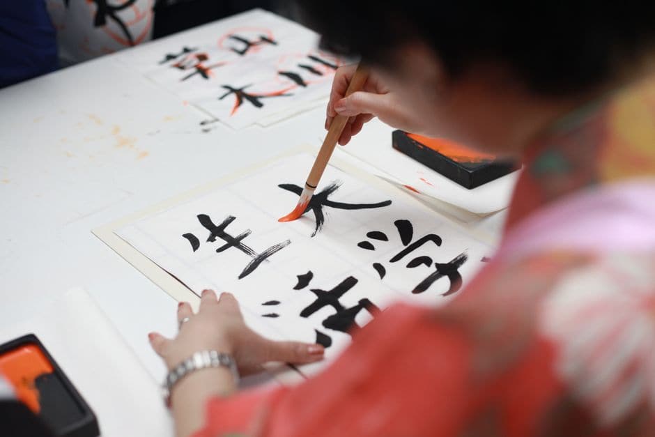 筆で漢字を書いている人の手元