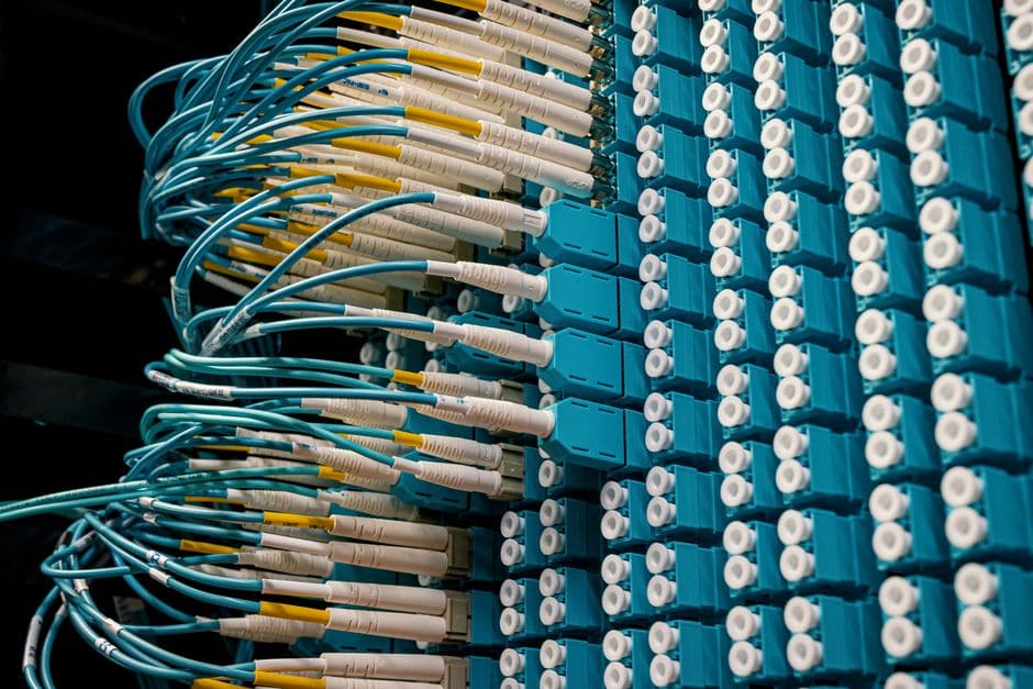 データセンターのパッチパネルに規則正しく挿された、水色の光ファイバーケーブル